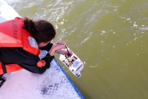 A student lowers a remotely operated vehicle (ROV) over the side of LUMCON's R/V Acadiana before testing the vehicle in the ocean. This ROV was constructed by students at an ROV-building workshop held at LUMCON in 2016.